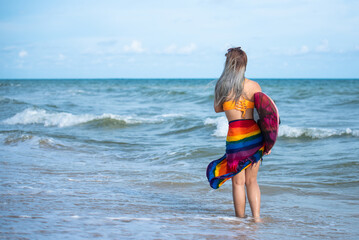 Asian beautiful young girl in bikini holding a surfboard at the beach.Summer Vacation. Water Sport.