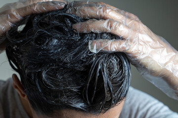 Closeup woman hands dyeing hair. Middle age woman colouring dark hair with gray roots at home