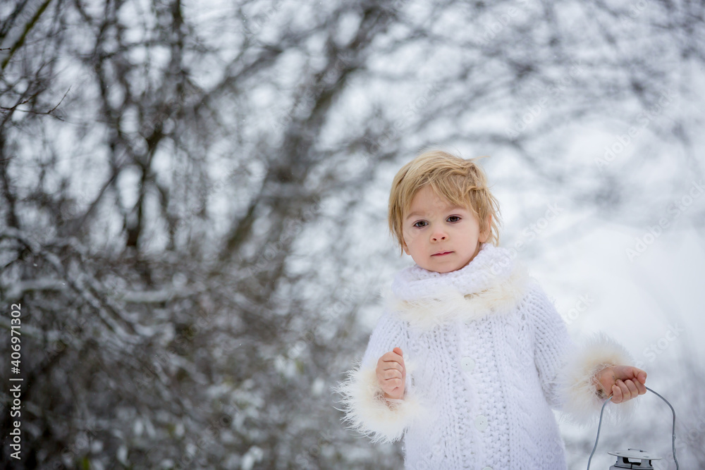 Sticker Beautiful blond toddler child, boy with white knitted handmade overall, holding lantern in the snow