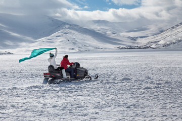 Fototapeta na wymiar People on the snow sled on the frozen Cildir Lake (Cildir Golu) in Ardahan nearby Kars, Turkey