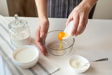 The process of making homemade dessert. Ingredients for dessert with cream cheese on a white background. The woman makes the mixture for the dough.