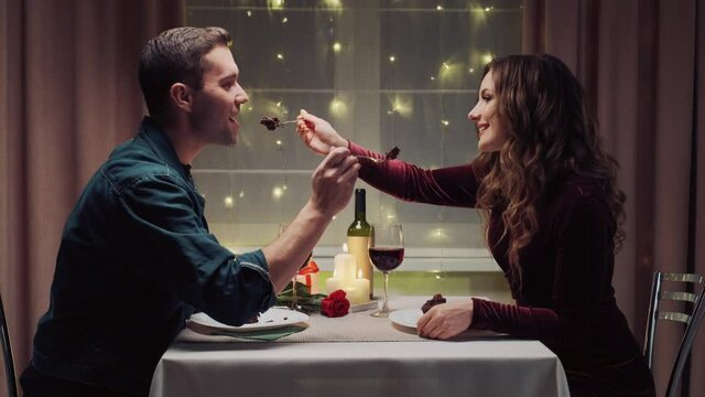 A man and woman in love eat a chocolate cupcake in the evening at home. Valentine's Day. A romantic dinner by candlelight.