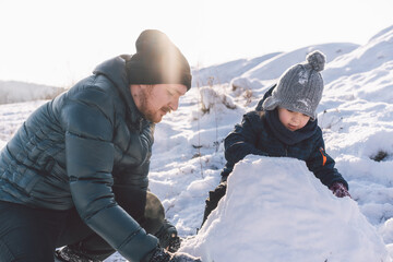 Fototapeta na wymiar Happy dad and little boy playing with snow. Winter holiday. 
