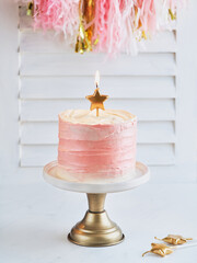 Happy birthday cake shot on a white light background with golden stars candles and space for text....