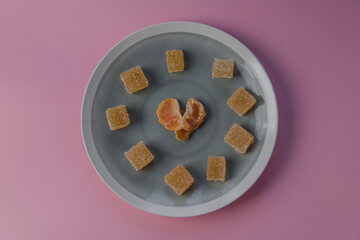 heart shaped malmalade and dried mandarin, on a pink background. Top view