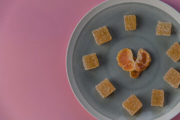 heart shaped malmalade and dried mandarin, on a pink background. Top view