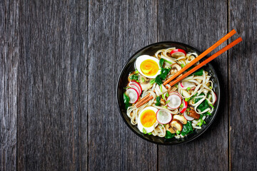 Udon noodle soup on a black plate, copy space