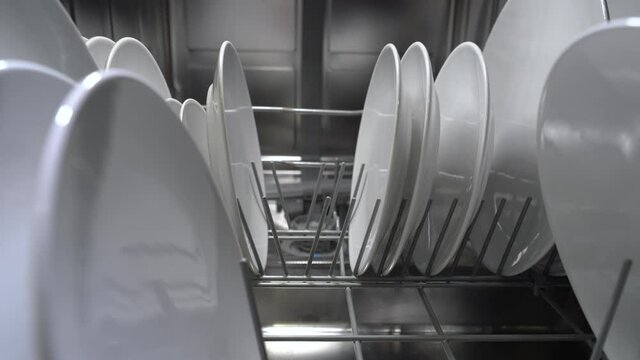 Backward Dolly Shot Of A Man Emptying The Dishwasher. Close Up View.