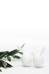 Obraz na płótnie Canvas Minimalistic Easter concept on a white background. White Easter eggs with bunny ears