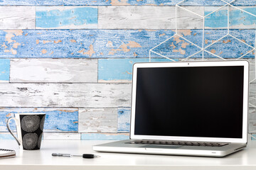 Home office. Open laptop with blank screen. A wall made of old boards. Mockup. Copy space.