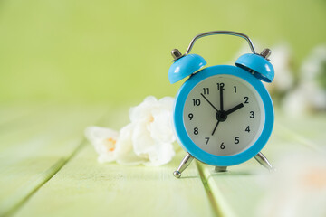 Spring time daylight saving concept - with alarm clock and flowers, copy space