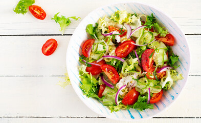 Fresh tomatoes with cucumber, lettuce, red onion and spices in a white bowl.  Concept healthy appetizer. White wooden background. Top view, overhead, copy space