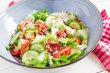 Ketogenic salad with prosciutto, tomatoes, cucumber, lettuce, red onion  and cheese  in  bowl.  Concept healthy appetizer. Keto, paleo food.