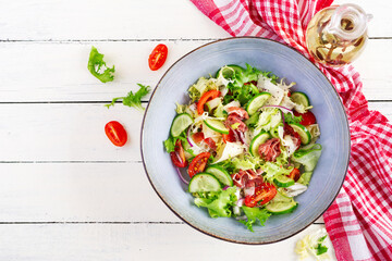 Ketogenic salad with prosciutto, tomatoes, cucumber, lettuce, red onion  and cheese  in  bowl.  Concept healthy appetizer. Keto, paleo food. Top view, overhead, copy space