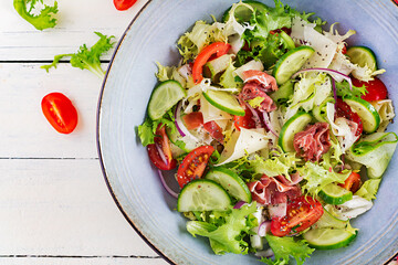 Ketogenic salad with prosciutto, tomatoes, cucumber, lettuce, red onion  and cheese  in  bowl.  Concept healthy appetizer. Keto, paleo food. Top view, overhead, copy space