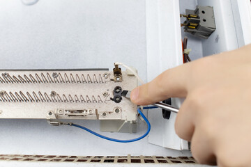 An electrical repairman repairs a convector. A close-up of an open heater and its interior. Technical assistance concept