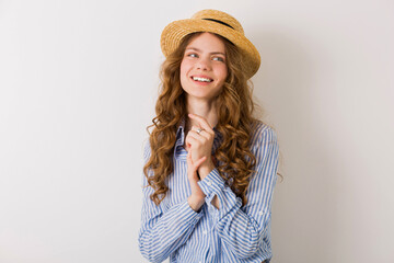 young beautiful stylish woman in summer style outfit posing on white wall wearing straw hat