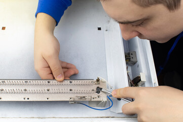 An electrical repairman repairs a convector. A close-up of an open heater and its interior. Technical assistance concept