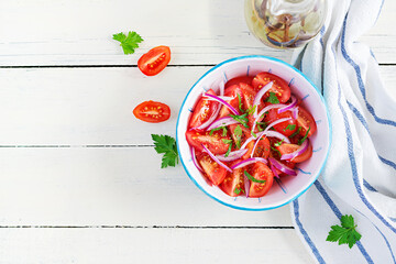 Fresh tomatoes with red onion and spices in a blue bowl.  Concept healthy appetizer. White wooden background. Top view, copy space