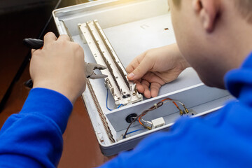 An electrical repairman repairs a convector. A close-up of an open heater and its interior. Technical assistance concept