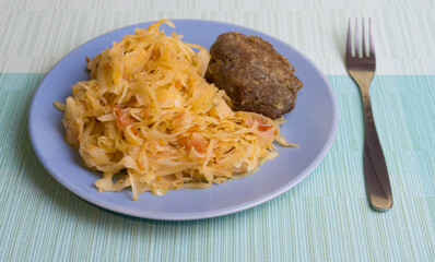 Stewed white cabbage with a cutlet steak on a plate. A dish of Russian, Polish cuisine. Garnish in the USSR.