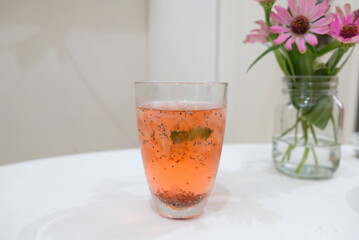 A glass of aloe vera ice drink with syrup on the table.