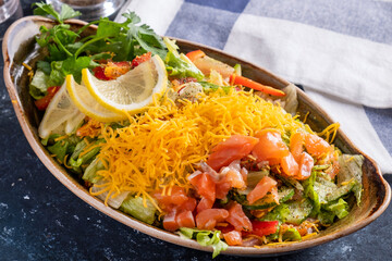 Salmon salad with fresh vegetables and yellow cheese. Closeup