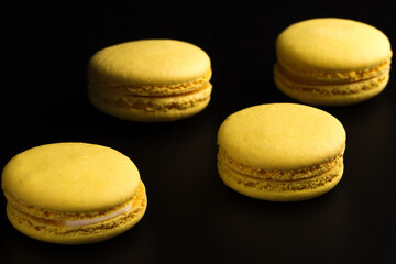 French cookies. Yellow macaroons isolated on a dark, black background. almond cookies.