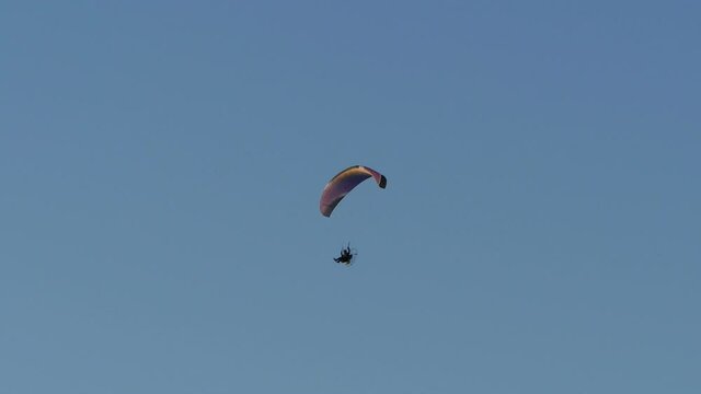 paraglider with a motor flies high in the blue sky