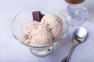 Homemade ice cream with chocolate chips in a bowl. Three balls of ice cream and a cup with coffee. Close-up.