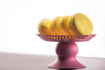 French cookies. Yellow macaroons, on a pink vase isolated on a dark, black background. almond cookies.