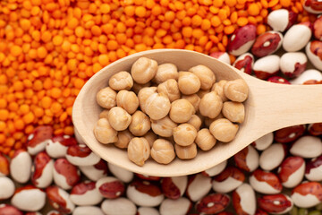 Uncooked dried chickpeas in wooden spoon close up. Heap of legume chickpea background