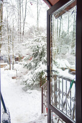 View of the snow-covered courtyard through the glass open door of the cottage.