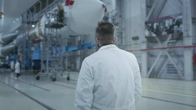 A scientist engineer inspects a spaceship, makes notes on a tablet. A space rocket in a military hangar being prepared for launch. Space technologies. Construction of Heavy Rocket. Humanity in Space