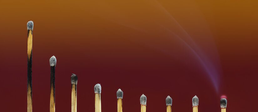 Decline, decadence and stagnation concept. Burnt matches decreasing in length, forming a falling graph. Dark red background, copy space. - Powered by Adobe