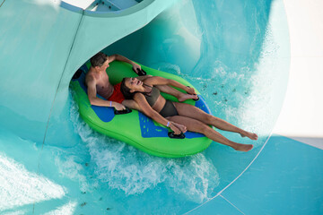 Girl and boy in water Park. Fun on the water. Teen girl and boy having fun in the water slider ....