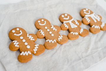 Smiling gingerbread man with sugar, spices, and vintage rolling pin on rustic, textile linen background.