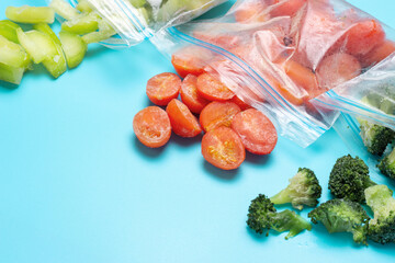 Packets of scattered and frozen vegetables on blue plate with copy space