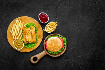 Classic burger served on wooden cutting board with french fries and fried chicken