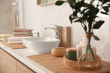 Fototapeta na wymiar Fresh towels and beautiful branches near stylish vessel sink in bathroom. Interior design