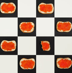 Salmon caviar canapes pattern on chess bords, top view