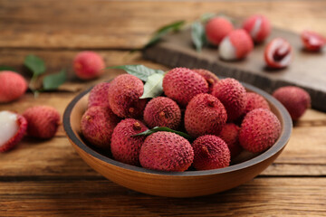 Fresh ripe lychee fruits in bowl on wooden table