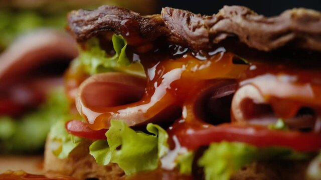 Close up red sauce on sandwich with vegetables.