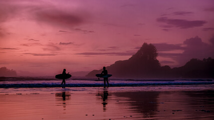 Tofino Vancouver Island Pacific rim coast, surfers with board during sunset at the beach, surfers...