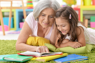 Grandmother reading book with her little granddaughter