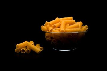 Dry raw rigatoni pasta on dark background