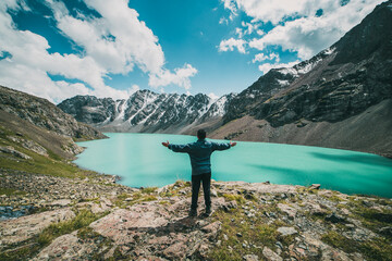 A guy celebrating arrival at Ala Kul lake at 3600 meters high in kyrgyzstan - obrazy, fototapety, plakaty