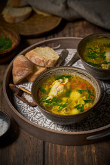 Chicken soup in clay bowls, bread on rustic background