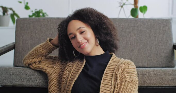 Portrait afro american calm woman resting relaxes in cozy living room leaning her hand on new sofa, ethnic girl homeowner enjoying house bought apartment, successful lazy lady sitting with eyes closed