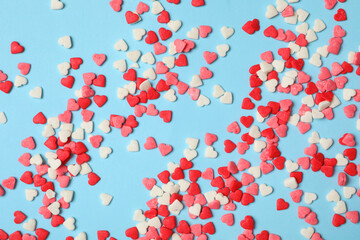 Bright heart shaped sprinkles on light blue background, flat lay